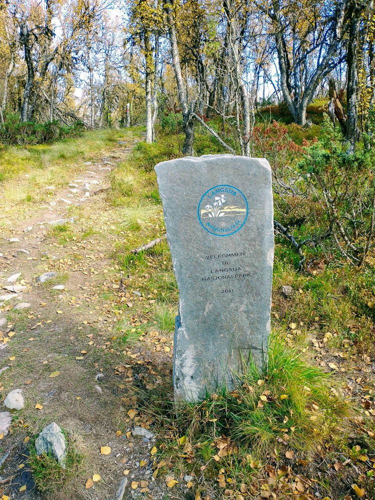 Bildet viser stein med hvitt og blått symbol for inngang til Langsua nasjonalpark